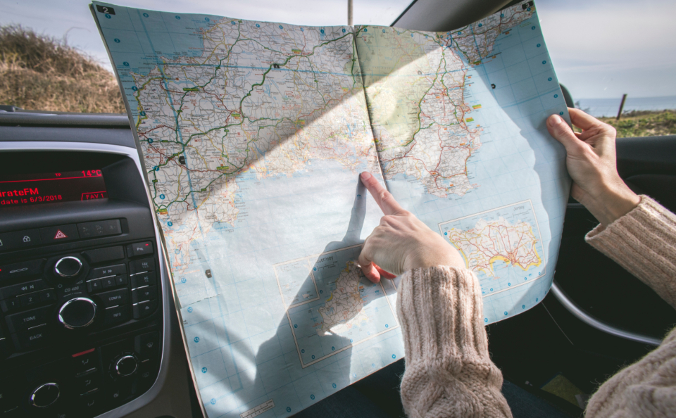 A hand pointing at a world map, planning a luxury travel itinerary