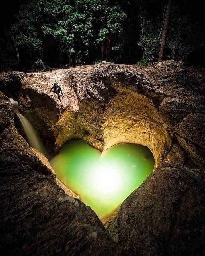 A romantic heart-shaped rock formation looking out over a turquoise tropical lagoon.