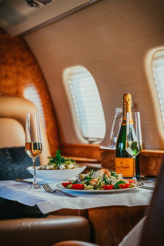 seat on a flight with expensive drinks and food by a window. 
